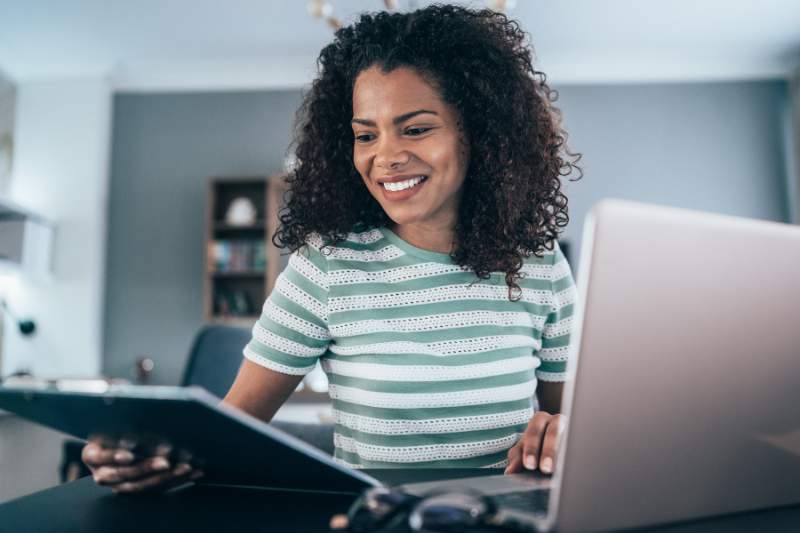 Woman with laptop and tax prep checklist, preparing essential documents to file her taxes.