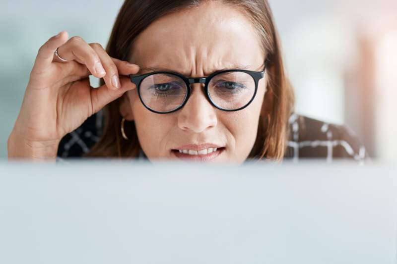 Confused woman staring at her computer screen, unsure why her tax return was rejected due to the wrong prior year AGI.