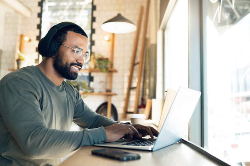 A happy man working on his laptop from home, representing remote job opportunities and work-from-home careers.