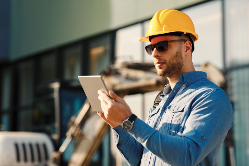 Independent contractor wearing a hard hat and using a tablet, exploring tax deductions to reduce taxable income and maximize savings this tax season.