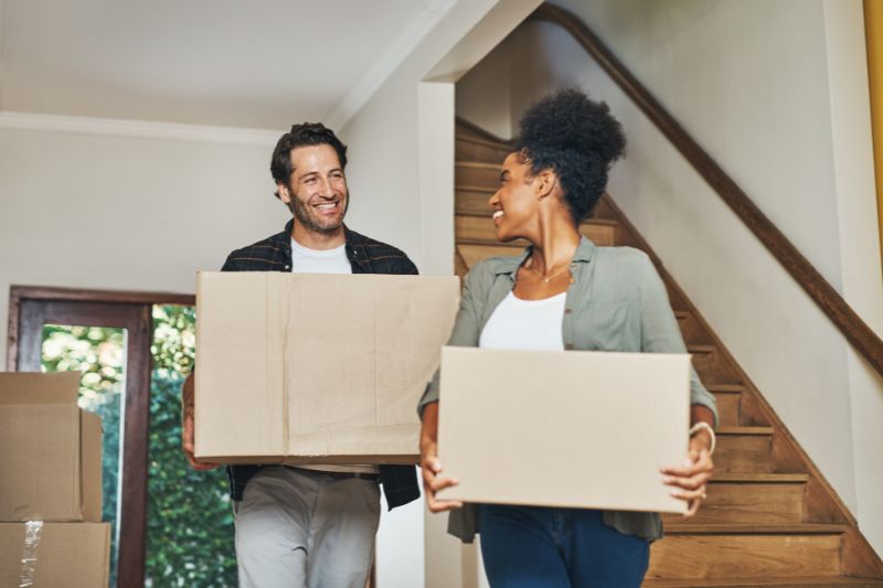 Couple moving boxes into their new home, highlighting tax deductions for homeowners.