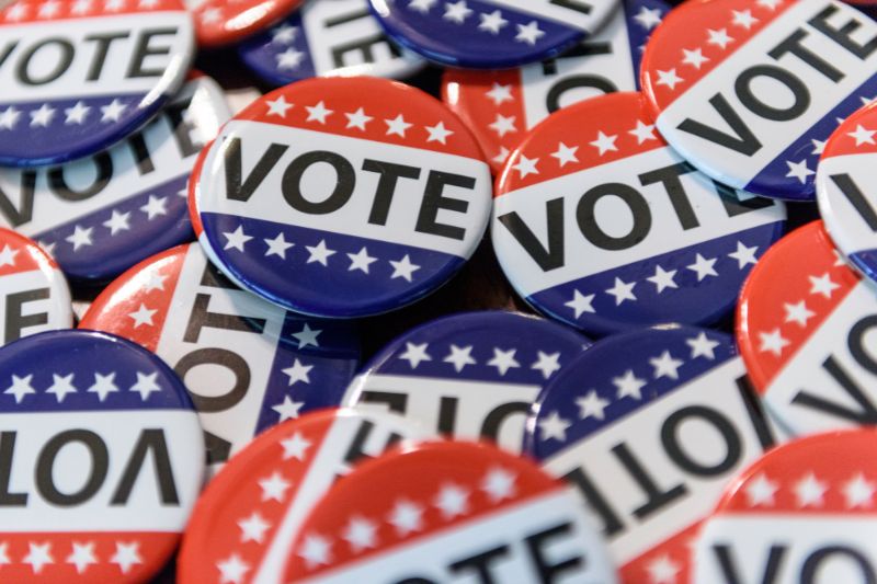 Close-up of 'vote' button pins, symbolizing political contributions and their potential tax implications.