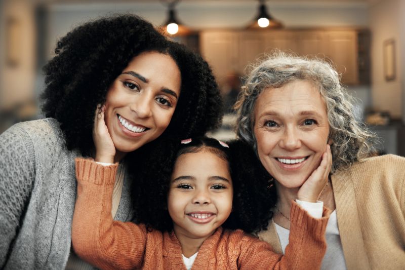 A grandmother, mother, and daughter smiling together, representing family support and the Credit for Other Dependents.