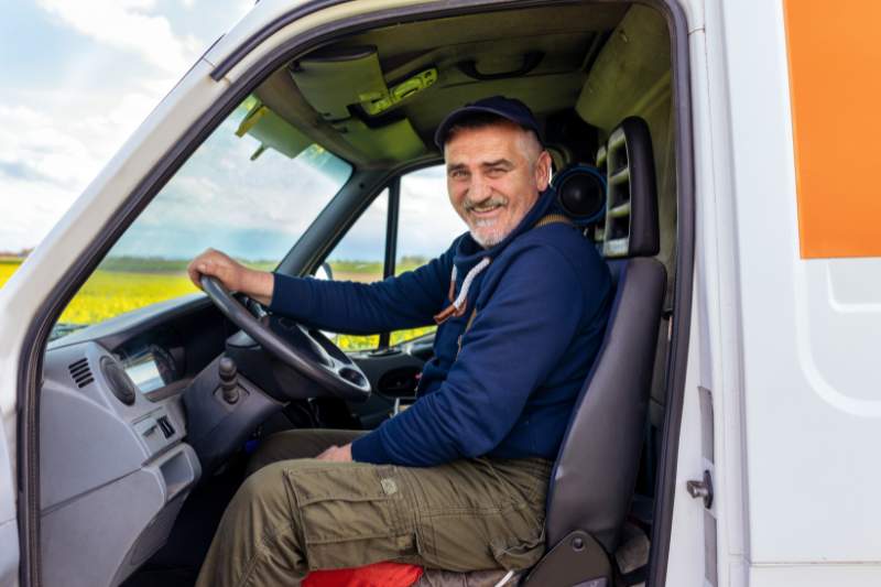 Happy delivery man smiling while sitting in his truck, illustrating the concept of claiming mileage for taxes.